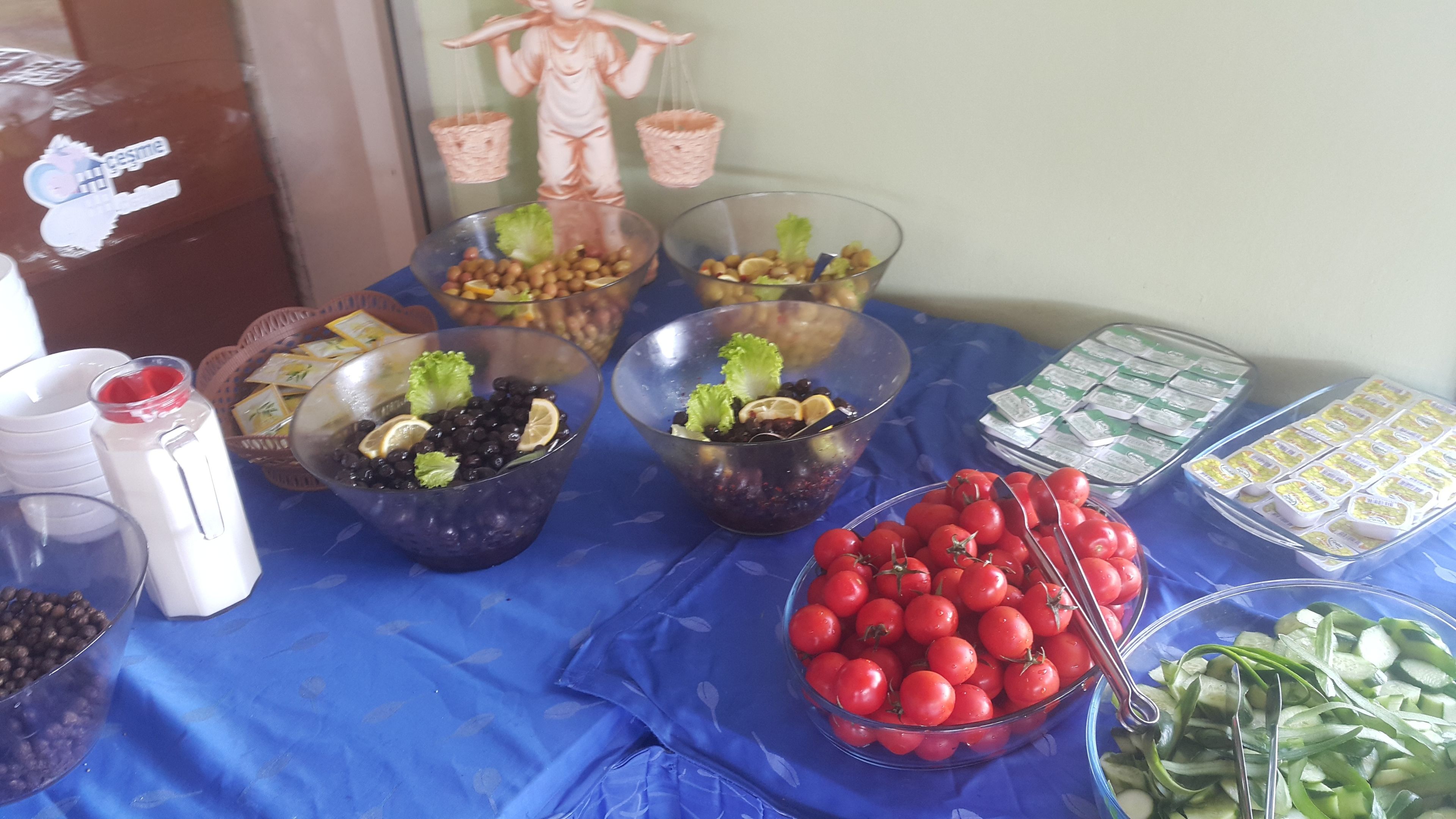 Una mesa con diferentes alimentos, incluyendo tazones de frutos rojos, tomates y rodajas de pepino.