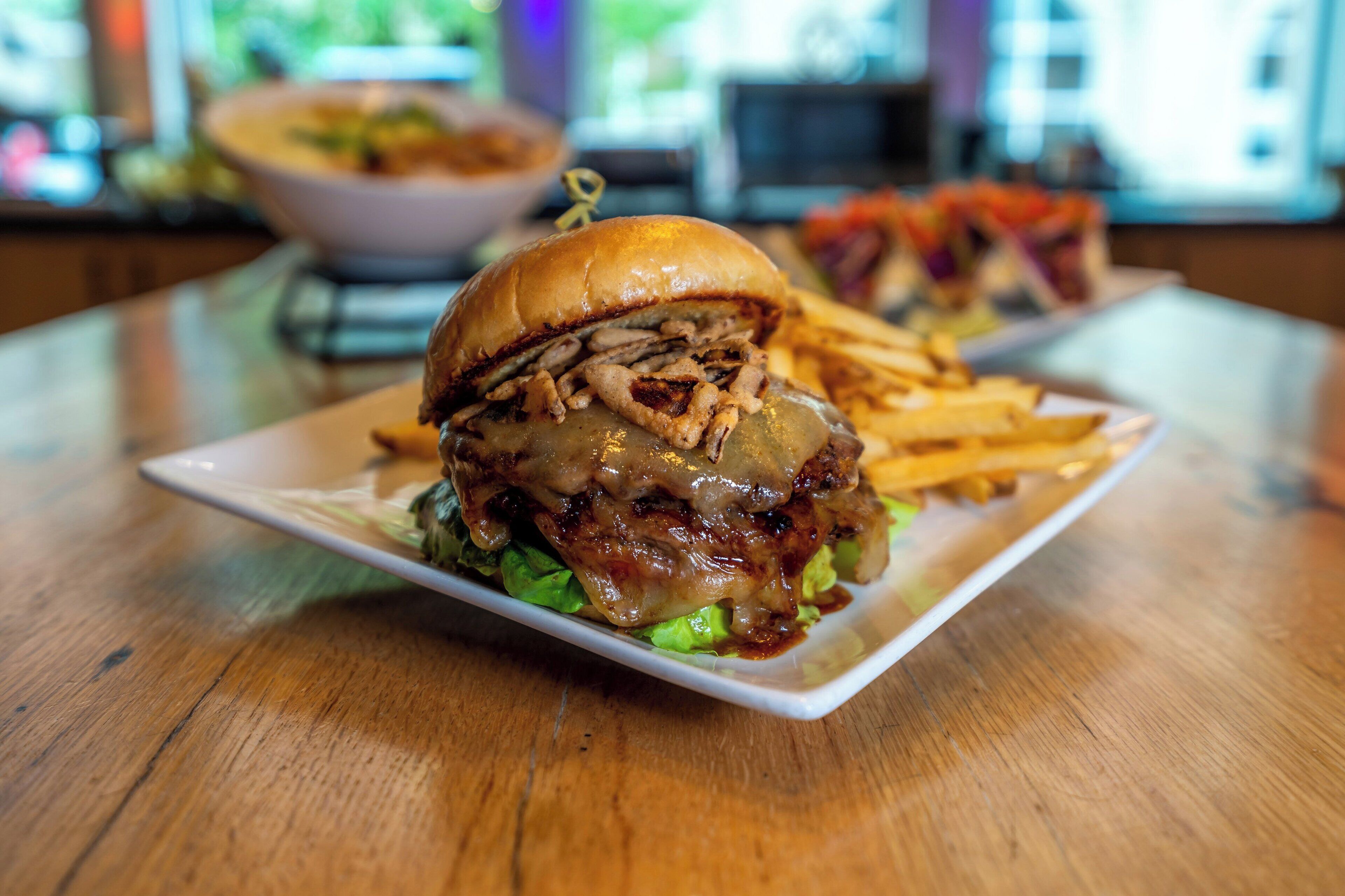 Une assiette avec un hamburger et des frites, posée sur une table en bois.
