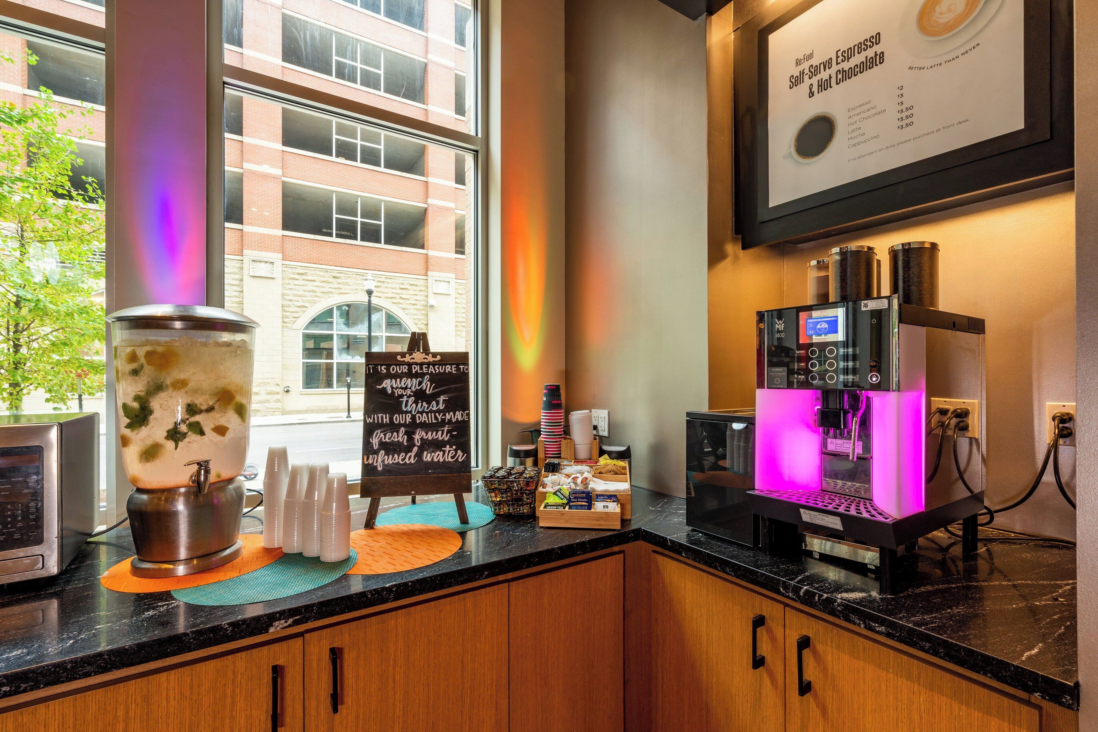 A coffee shop counter with a coffee machine, a water dispenser, and a menu board.