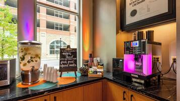 A coffee shop counter with a coffee machine, a water dispenser, and a menu board.
