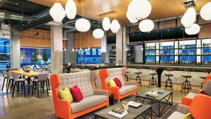 A modern bar area with sofas, tables, and a bar stocked with bottles.