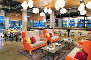Zona de bar moderna com sofás, mesas e balcão repleto de garrafas.