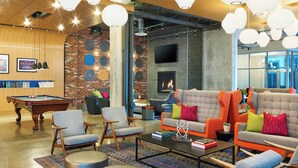 A modern lounge area with a pool table, comfortable seating, a fireplace, and a brick accent wall.