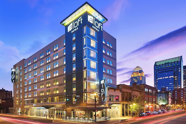 A modern hotel with a prominent 'Aloft Hotels' sign, multiple floors, and a corner location with a view of the city skyline. - Aloft by Marriott Louisville Downtown (Louisville)