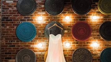 A wedding dress hanging on a wall with a brick pattern and decorative plates.
