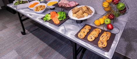 Una mesa de buffet con diferentes opciones de comida, como ensaladas, carnes y pasteles.