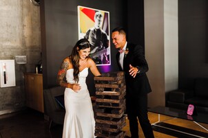 Una recepción de boda con una torre de bloques de madera, una pared moderna con un cartel y un sofá oscuro.