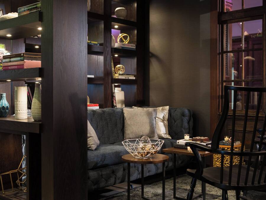 A cozy living room with a dark-colored sofa, a wooden coffee table, and a bookshelf filled with books and decorative items.