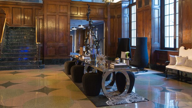 A grand lobby with a marble staircase, a central table with decorative items, a large window with a view, and a cozy seating area. - Renaissance Albany Hotel (Albany)