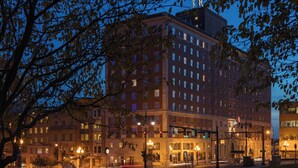 A multi-story hotel with a classic architectural design, featuring a prominent entrance with a canopy and a flagpole. - Renaissance Albany Hotel (Albany)