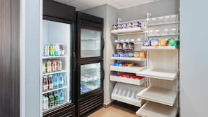 A small, well-organized pantry with shelves stocked with snacks and beverages. - Spark by Hilton Rochester South (Rochester)
