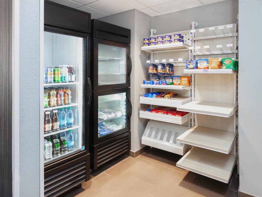 Uma despensa pequena e bem organizada, com prateleiras repletas de lanches e bebidas.