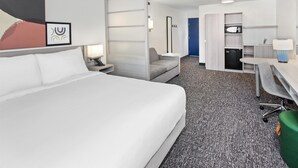 A hotel room with a large bed, a desk, a chair, and a kitchenette. - Spark by Hilton Rochester South (Rochester)