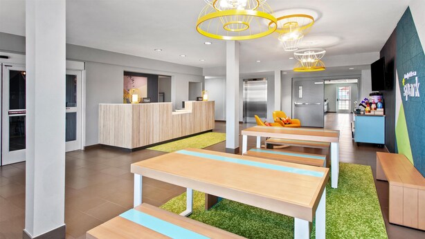 A modern hotel lobby with a reception desk, seating area, and a kitchenette. - Spark by Hilton Rochester South (Rochester)