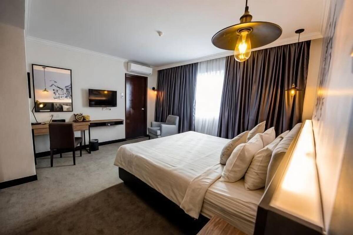 A hotel room with a bed, desk, chair, and TV.
