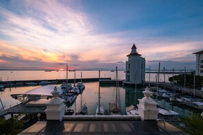 A marina with boats docked, a prominent white tower, and a sunset in the background. - Home Suites by Marina (George Town)