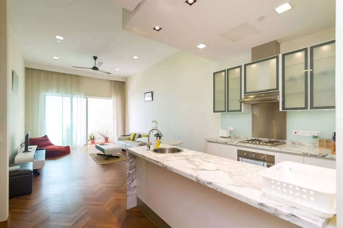 A modern kitchen with a marble countertop, stainless steel appliances, and a large window.