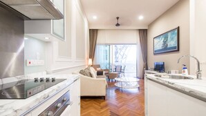 A modern kitchen with a built-in stove, a dining area with a round table, and a view of the Eiffel Tower through the window. - Home Suites by Marina (George Town)