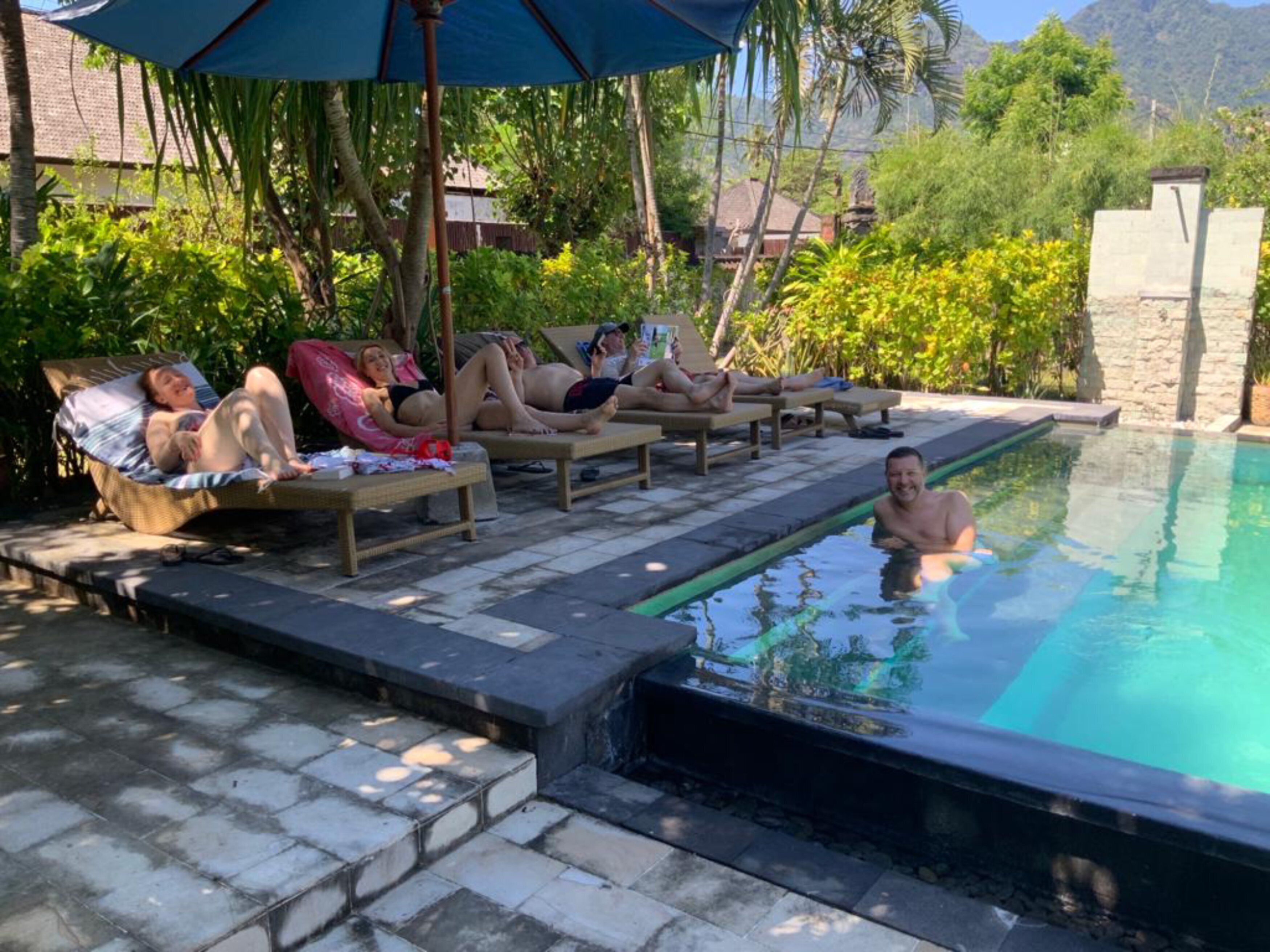 Un espace aménagé au bord de la piscine, avec des chaises longues et une personne dans l’eau.