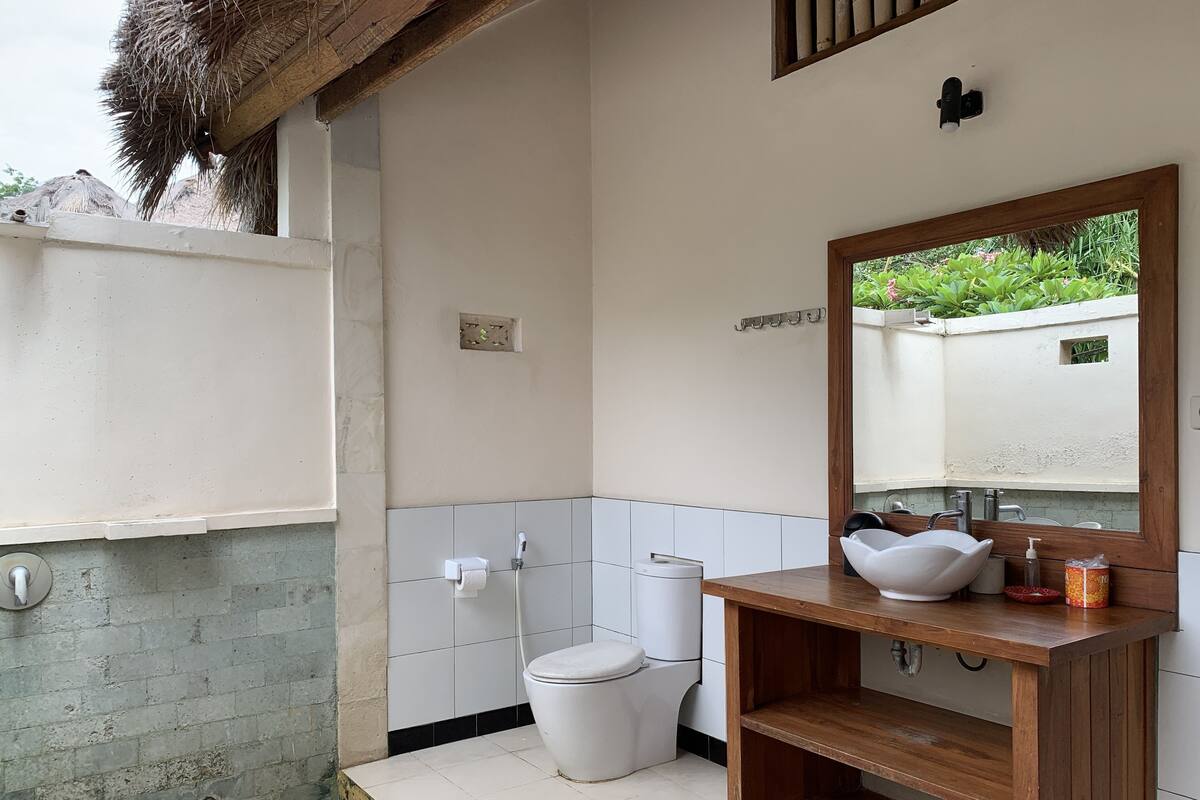 A bathroom with a white toilet, a wooden vanity with a white sink, and a mirror.