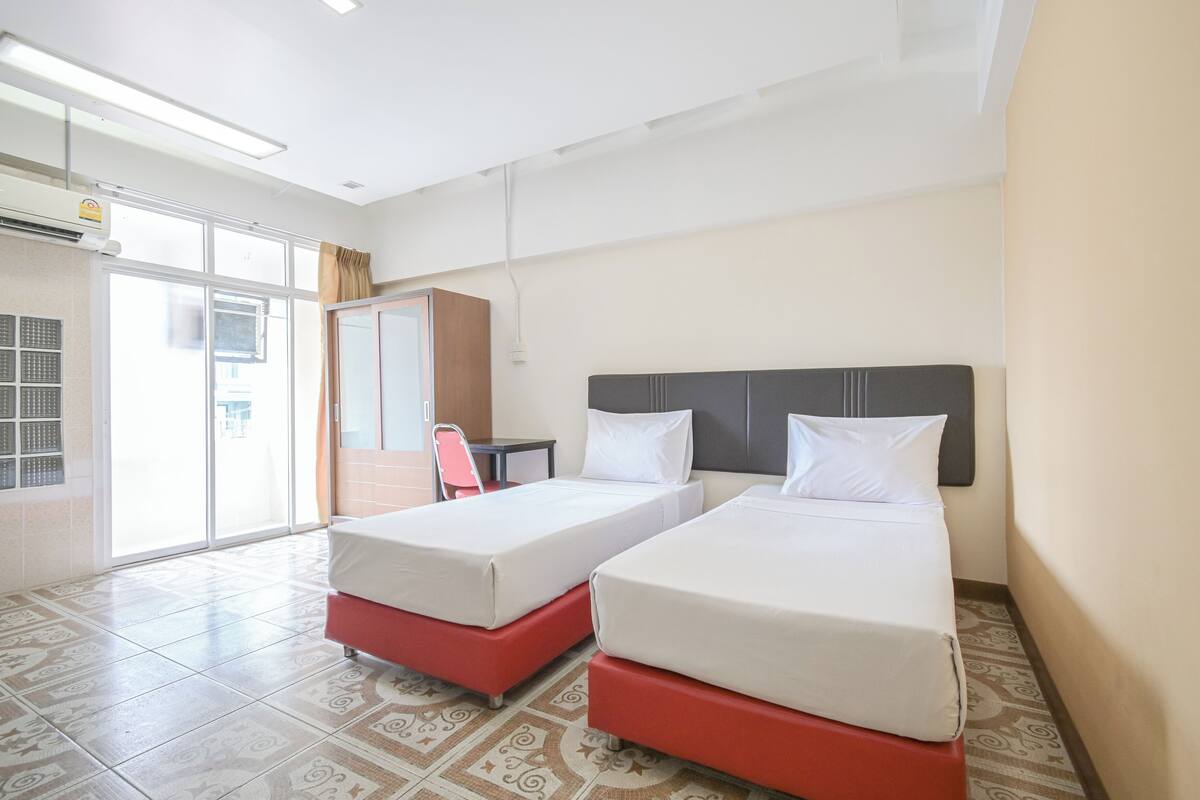 A hotel room with two beds, a desk, and a chair.