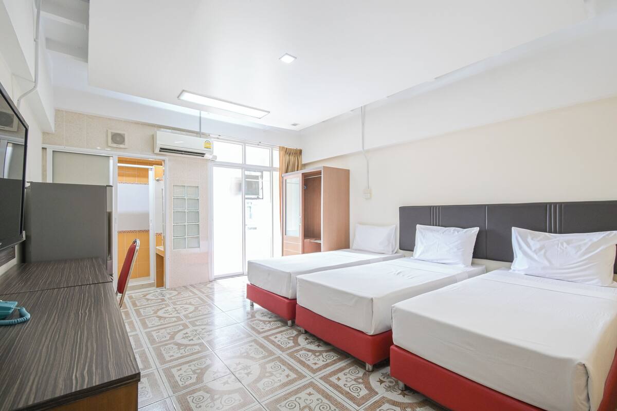 A hotel room with two beds, a desk, and a wardrobe.