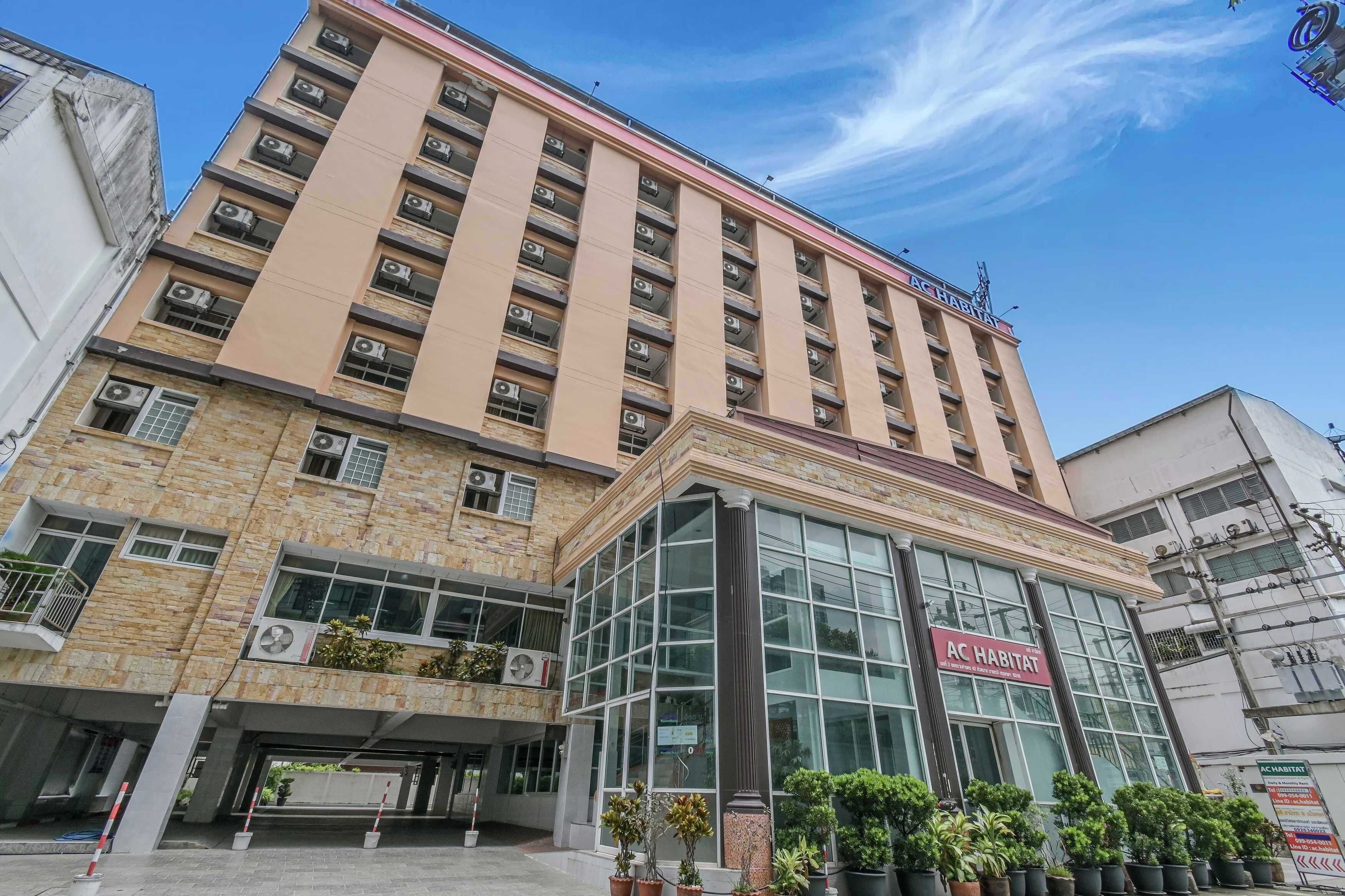 A multi-story hotel with a prominent AC HABITAT sign, large windows, and a stone facade.