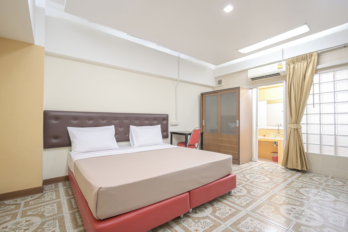 A hotel room with a bed, a wardrobe, a small table, and a window with curtains.
