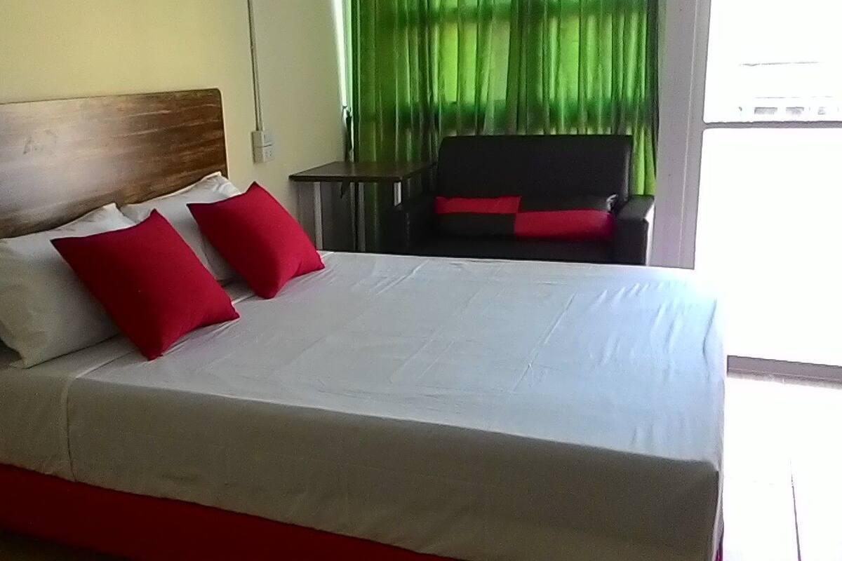 A bed with a wooden headboard, white bedding, and red pillows.
