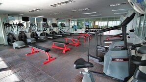 Ein Fitnessstudio mit Laufbändern, Crosstrainern und einer Gewichthecke.