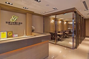 Een hotel receptie met een modern ontwerp, met een receptiebalie, zithoek en glazen scheidingswand.