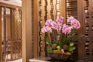 Een pot orchideeën op een tafel in een kamer met houten lambrisering.