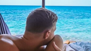 A person lying on a bed with a view of the ocean through a window. - P.D. Beach Resort (Koh Tao)