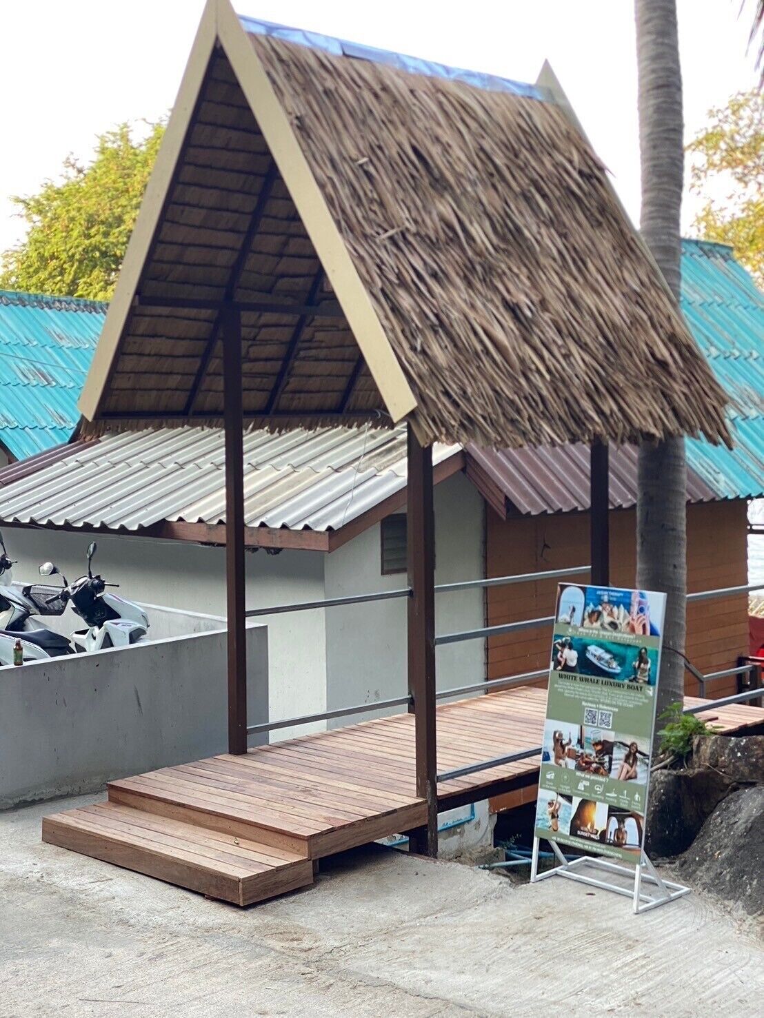 A small structure with a thatched roof, a wooden platform, and a signboard.