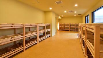 A room with multiple wooden shelves filled with wicker baskets, a wooden floor, and a window on the right.