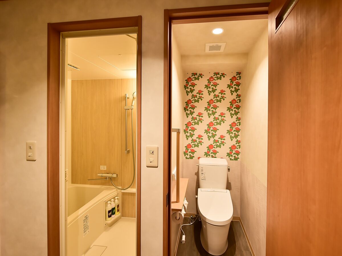 A compact bathroom with a toilet, shower, and a small sink.