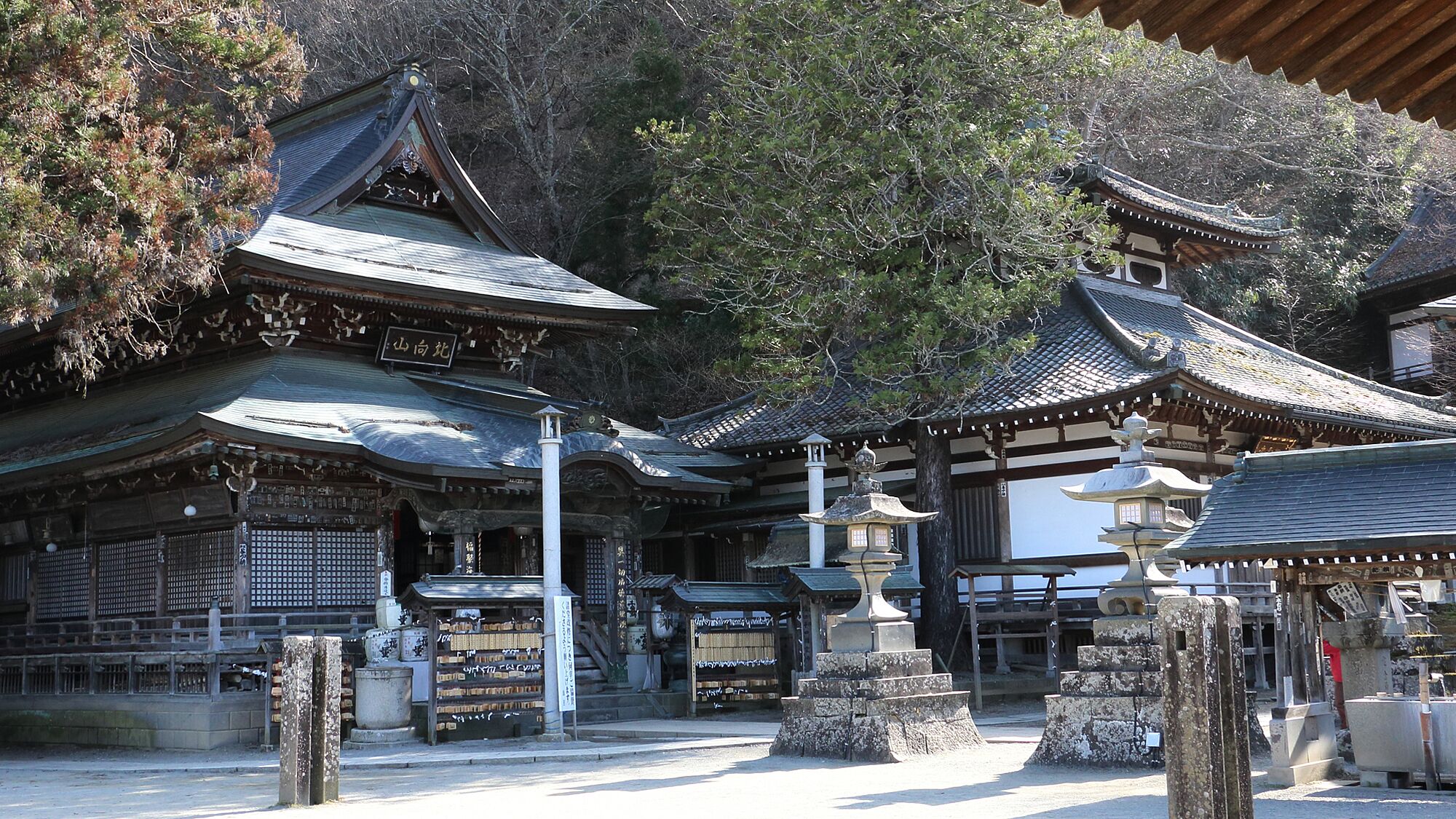 Un temple japonais traditionnel composé de plusieurs bâtiments, de structures en bois et de lanternes en pierre.
