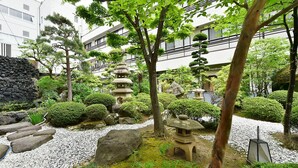 A traditional Japanese garden with stone lanterns, a koi pond, and various shrubs. - Hotel Marusansou (Chikuma)