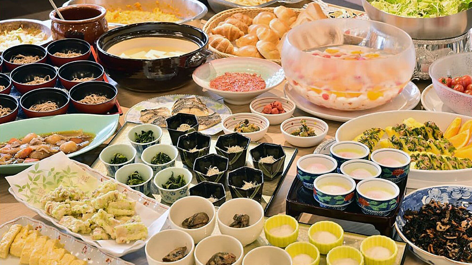 A variety of dishes and food items on a table, including bowls of soup, plates of vegetables, and other food preparations.