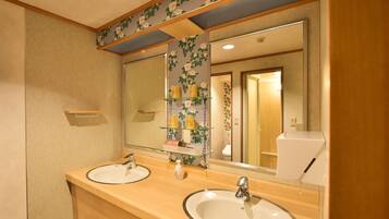 A bathroom with two sinks, a mirror, and a shelf with toiletries.