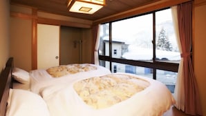 Une chambre à coucher avec un grand lit, un plafond en bois et une fenêtre donnant sur des bâtiments enneigés.