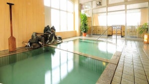 Une piscine intérieure dotée d’un plancher en bois, d’une pagaie et d’une sculpture en pierre.