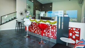 A modern reception area with a glass partition, a reception desk, and a staircase. - Indra Hotel (Ipoh)