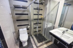 A modern bathroom with a glass-enclosed shower, a white toilet, and a sink with a mirror. - Indra Hotel (Ipoh)