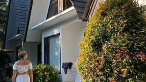Una casa residencial con techo inclinado, porche delantero y un jardín bien cuidado.