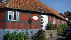 A traditional building with a tiled roof, a white door, and a sign that reads "Hotel Bellevue". - Pension Holmegaard (Allinge)