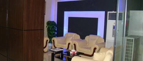 Ein modernes Wohnzimmer mit Flachbildfernseher, Ledersofas, einem Couchtisch und einer Topfpflanze.