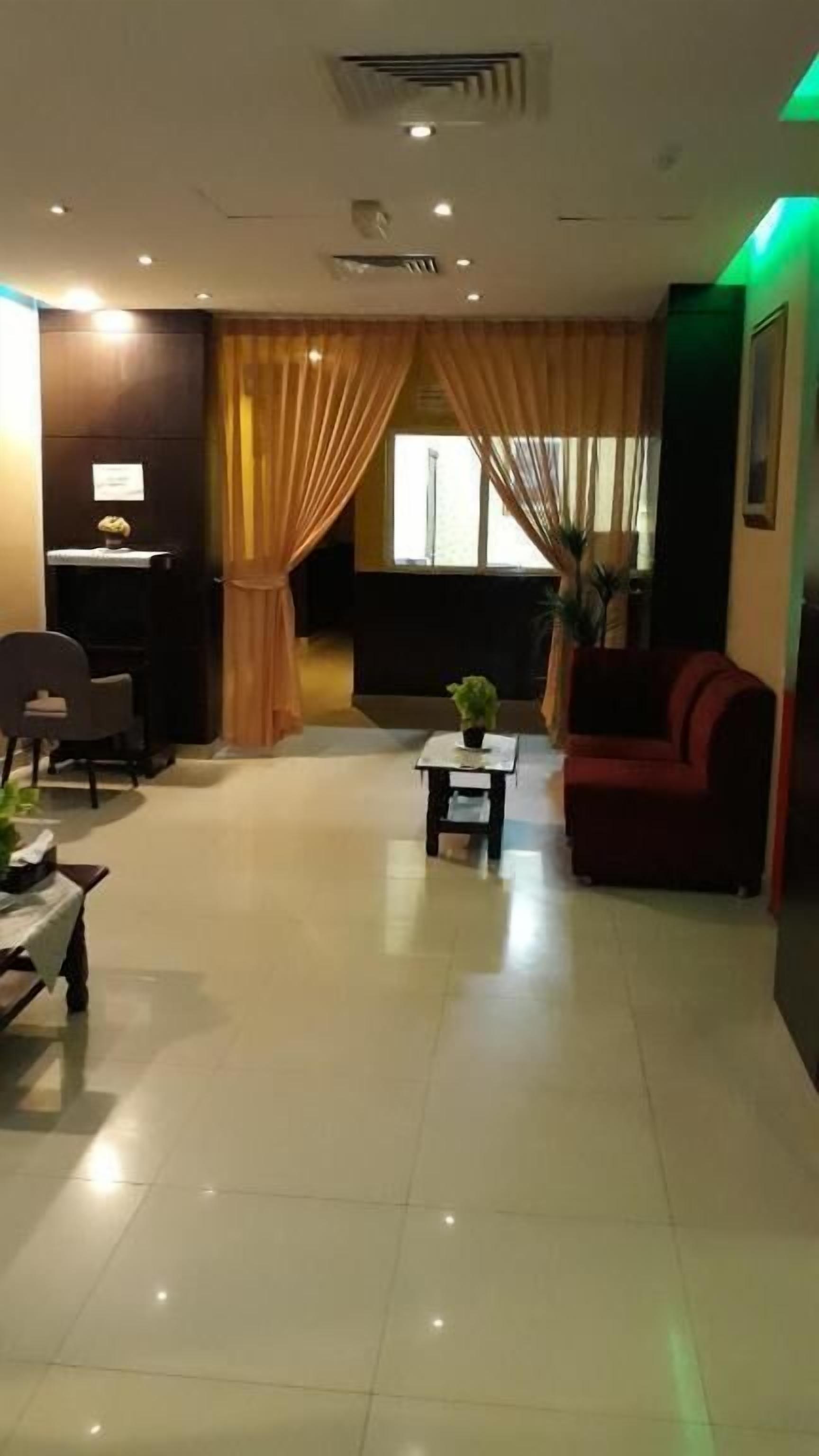 Un hall d’hôtel comprenant un comptoir d’accueil, un espace salon et une grande fenêtre avec des rideaux.