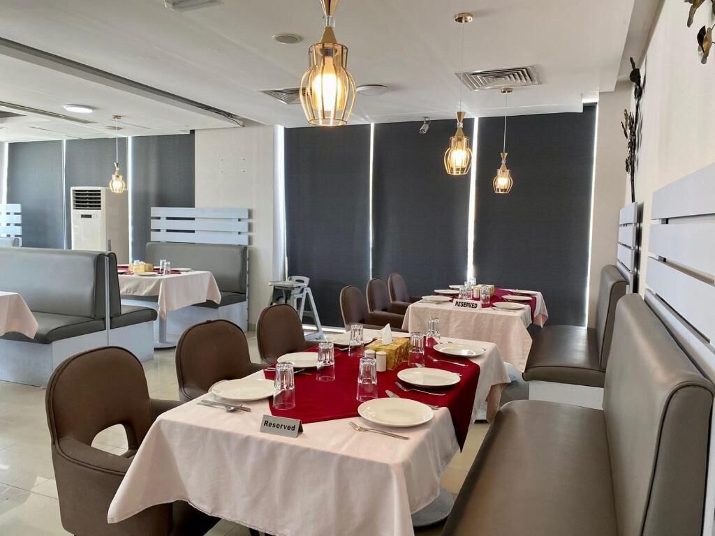 Un restaurante con mesas dispuestas para comer, una zona de bar y un área de estar.