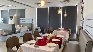 Un restaurante con mesas dispuestas para comer, una zona de bar y un área de estar.